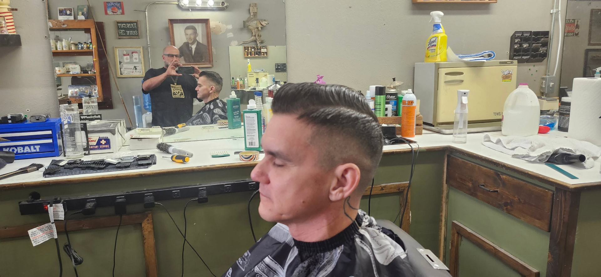 Slick back pompadour with a tight fade at Tommy's Barbershop